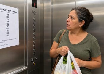 Lista de débitos aparece junto ao elevador do condomínio.