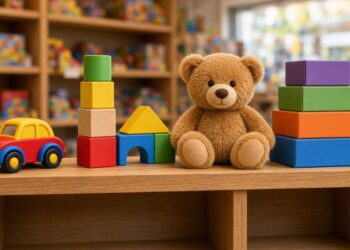 Brinquedos coloridos, como blocos de madeira, urso de pelúcia e carrinho, numa prateleira de loja